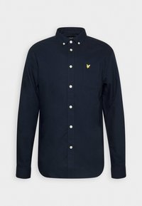 Camisa de botón de manga larga en algodón color navy. Presenta un bolsillo en el pecho con un logo de águila amarilla y botones blancos en la parte frontal. Textura suave.