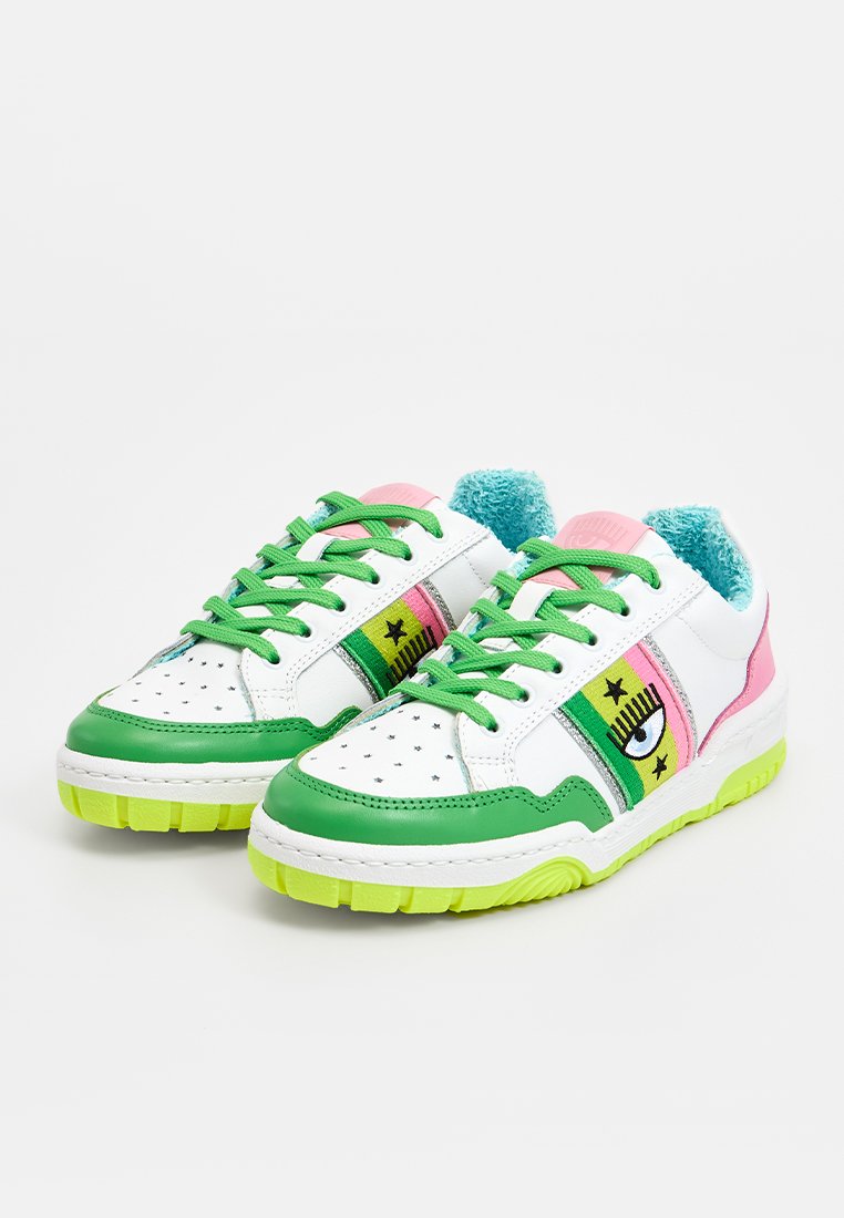 Zapatillas blancas con acentos en verde, rosa y turquesa. Presenta un gráfico de ojo, un patrón de estrellas y una lengüeta texturizada. Suela de goma gruesa.