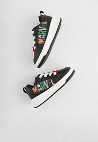 Baskets noires avec un graphique coloré "MARVEL", des lacets blancs, un onglet d'accent rouge et une semelle en caoutchouc texturée.