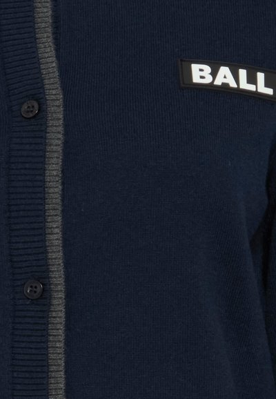 Jūras spēku krāsā pārklāts kardigāns ar ribotu tekstūru, vienu pogu un pelēku svītru pa priekšpusi ar melnu "BALL" uzšuvumu.