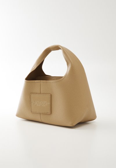 Petit sac à main en cuir beige de forme triangulaire, avec une poignée supérieure et un patch logo rectangulaire cousu sur le devant.