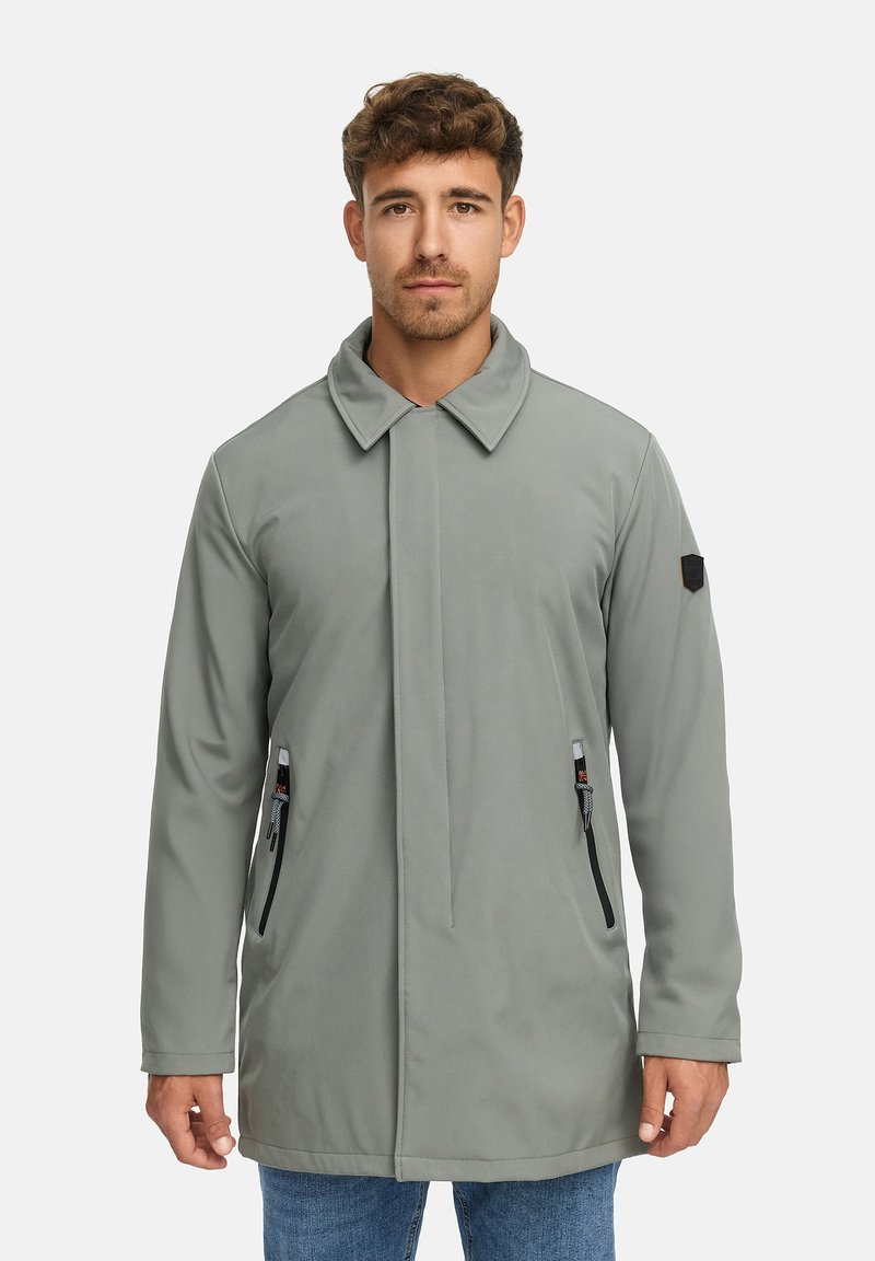 Cappotto grigio a maniche lunghe con colletto a pressione, tasche laterali con zip e un tessuto textures. Include una toppa con il logo sulla manica sinistra.