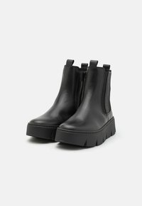Black leather ankle boots with elastic sides, rounded toe, and a thick, ridged sole. Smooth texture with pull tabs for easy wear.
