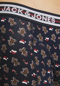 Marineblaue Boxerbriefs mit einem wiederkehrenden Muster aus Lebkuchenmännern und Zuckerstangen, versehen mit einem elastischen Bund in kontrastierenden Farben.