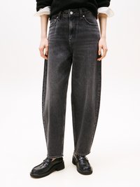 Jeans de ganga pretos de cintura alta com um corte solto, costuras em contraste e design de cinco bolsos. Combinados com mocassins pretos.
