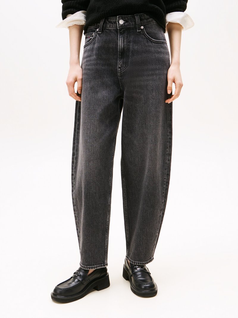 Jeans de ganga pretos de cintura alta com um corte solto, costuras em contraste e design de cinco bolsos. Combinados com mocassins pretos.