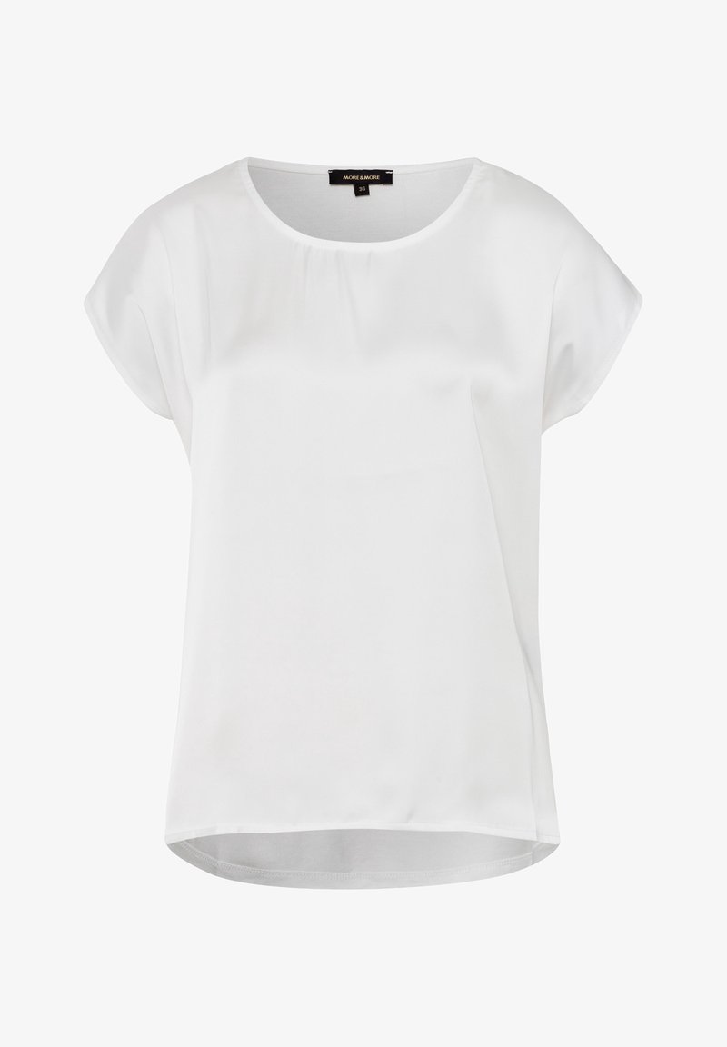 Blusa blanca de manga corta hecha de un tejido suave, con un escote redondo y un dobladillo trasero ligeramente más largo para un ajuste relajado.