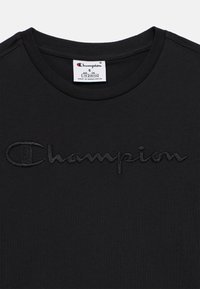 Μαύρο t-shirt με στρογγυλή λαιμόκοψη και μαύρο κεντητό λογότυπο "Champion" στο στήθος, με λευκή ετικέτα μεγέθους που δείχνει μέγεθος S και ηλικία 7/8.