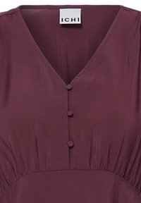 Robe bordeaux foncé avec encolure en V, boutons recouverts de tissu sur le devant, taille froncée et étiquette de la marque ICHI à l'intérieur du col.