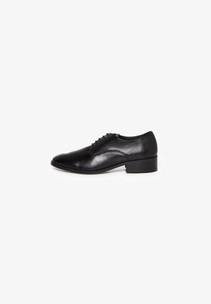 Chaussure habillée pour homme en cuir noir avec laçage fermé et petit talon carré, présentée en profil latéral sur fond blanc.