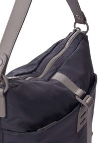 Bolso de hombro de nylon negro con correas y herrajes grises, que presenta una cremallera prominente y una superficie texturizada. Diseño compacto con un bolsillo lateral.