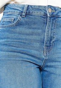 Ljusblå denimjeans med en figurnära design, synliga sömmar och en detalj med framfickor. Tyget har en lätt struktur.