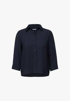 Námořnická modrá košile na knoflíky s texturovanou, žebrovanou tkaninou, dlouhými rukávy s manžetami a špičatým límcem. Klasický střih s zakřiveným lemem.