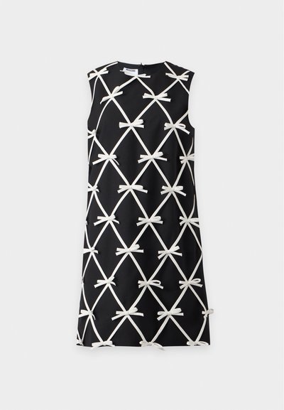 Robe noire sans manches avec un motif croisé blanc et de petits nœuds blancs à chaque intersection.