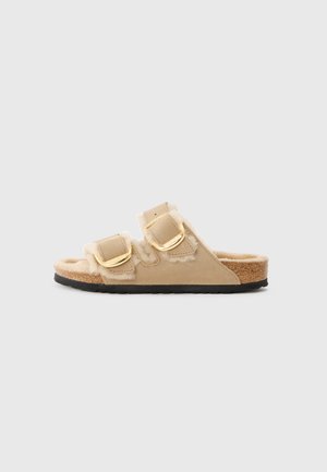 Bruna slide sandaletter med två justerbara spännen, mjuka fuskpälsdetaljer och en korkfotbädd, med en texturerad svart gummisula.