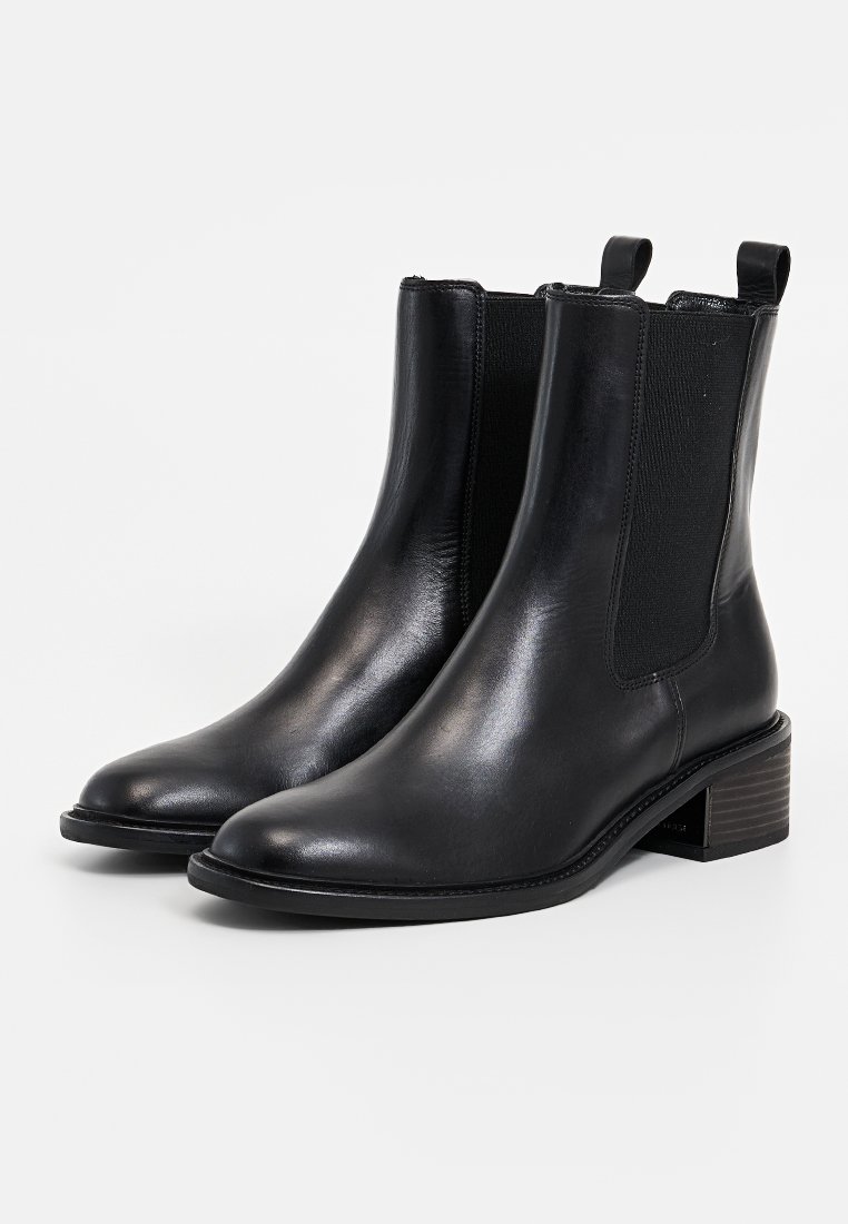 Schwarze Lederstiefeletten mit elastischen seitlichen Paneelen, runder Zehenpartie und niedrigem Blockabsatz. Glatte Textur und minimalistisches Design.