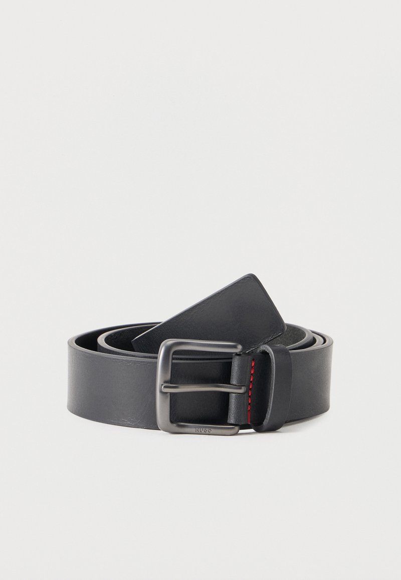 Μαύρη δερμάτινη ζώνη διπλωμένη με μεταλλική ορθογώνια αγκράφα και μικρή κόκκινη ραφή στη θηλιά, σε απλό λευκό φόντο.