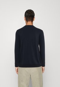 Marineblauwe sweatshirt met lange mouwen en geribde kraag en boorden, gemaakt van zachte stof. De zoom is aan de achterkant iets langer.