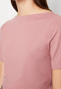 Tričko s krátkým rukávem a kulatým výstřihem v jemně růžové barvě z měkké bavlny. Má hladkou strukturu a minimalistický design, s čistým švem podél švů.