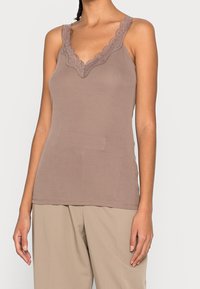 Top in cotone marrone a costine con bordi in pizzo scallop lungo il scollatura e le bretelle. Design aderente, texture morbida e stile minimalista.