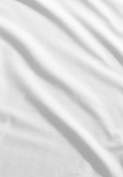 Smooth white fabric with soft diagonal shadows and subtle folds visible across the surface.