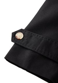 Czarny materiałowy mankiet z przeszytą krawędzią i okrągłym, jasnym guzikiem. Gładka faktura i dopasowany krój.