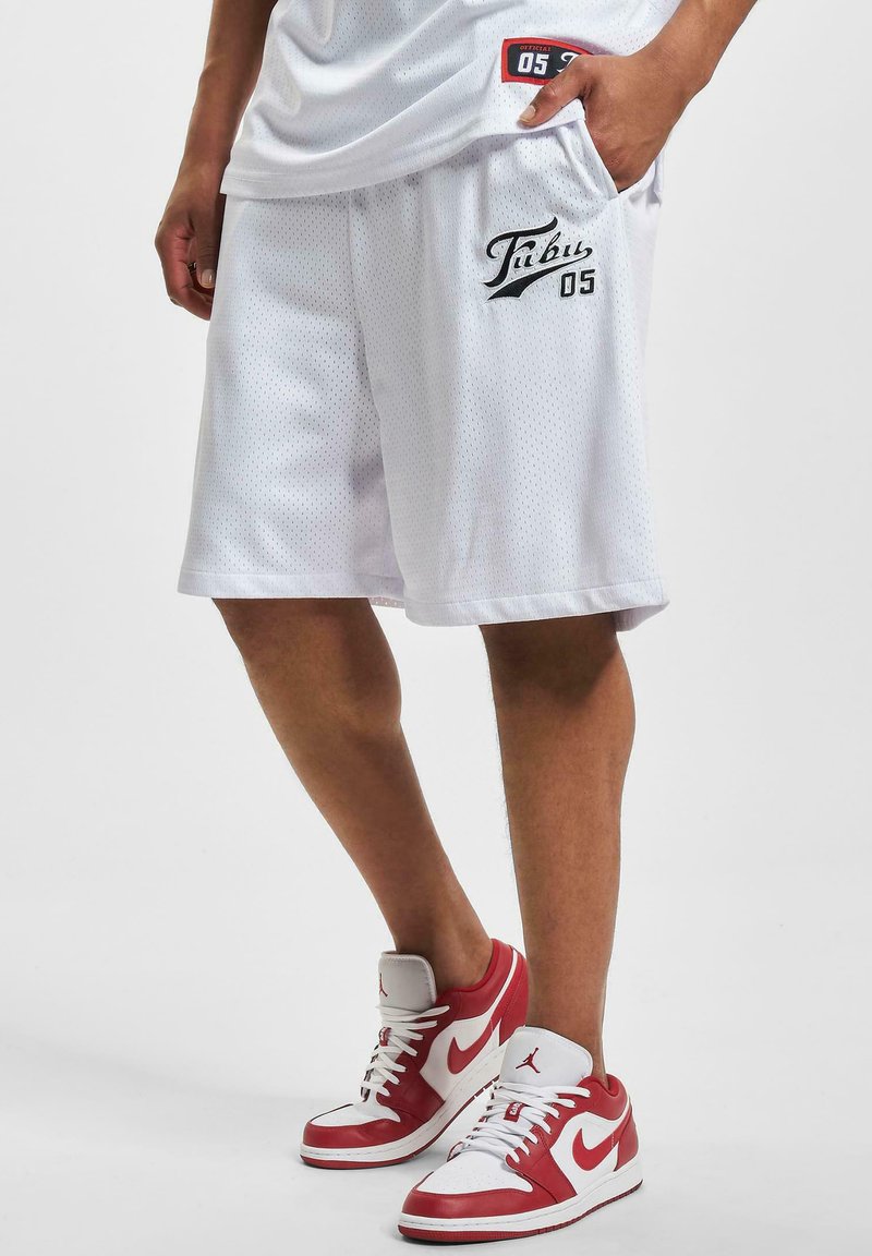 Hvite mesh basketballshorts med sidelomme, svart "Tabu 05"-logo og kontrastsøm. Kombinert med rød og hvit joggesko.