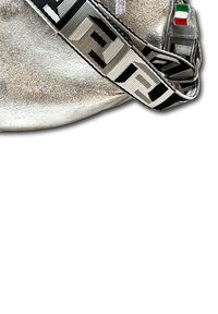 Zilveren metalen tas met een gestructureerd oppervlak, voorzien van een zwarte stoffen schouderband met een geometrisch patroon en een kleine Italiaanse vlag charm.