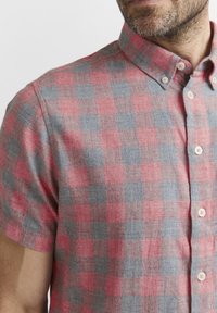 Camicia a maniche corte con bottone, in motivo tartan rosso e grigio, realizzata in tessuto testurizzato con bottoni piccoli e design del colletto classico.