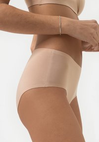 Culottes beiges sans couture en tissu doux, avec une taille lisse et des coutures minimales pour un ajustement confortable.