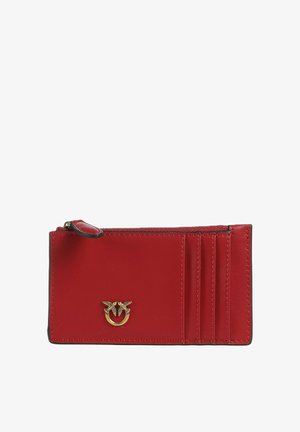 Tarjetero de cuero rojo con tres ranuras para tarjetas, un bolsillo para monedas con cremallera y un pequeño emblema de anillo dorado con dos pájaros en el centro delantero.