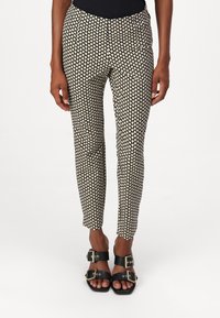 Black and cream patterned pants with a slim fit, featuring a small heart design, horizontal side pockets, and a mid-rise waist.
