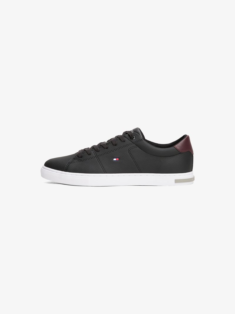 Sorte lærersneakers med hvit gummisåle, rund tå, snøring foran og burgunderfarget detalj ved hælen. Har en liten logodetalj.