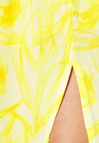 Tissu à motif floral jaune présentant un design divisé, mettant en avant une texture lisse et des couleurs vives avec des nuances plus claires.