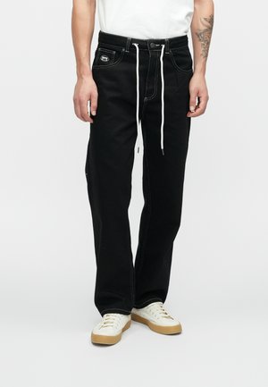 Mustad denim püksid laiema lõikega, valge nöör, kontrastne õmblus, küljetaskud ja brändipatch ees.