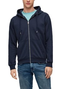 Sudadera con cremallera en azul marino, hecha de algodón suave, con cremallera frontal, capucha ajustable y dos bolsillos frontales. Lleva puesta una camiseta de color azul claro.