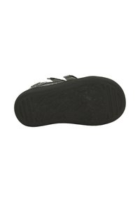 Semelle de chaussure en caoutchouc noir avec un motif texturé comportant diverses formes et rainures pour une traction et une adhérence. Deux bandes Velcro visibles en haut.
