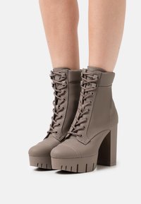 Bottines grises à talon bloc épais, matériau texturé, design à lacets, bout large et semelle plateforme côtelée.