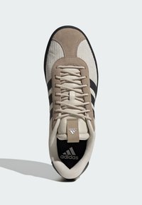 Tenisica od bež antilopa i teksturiranog tkanja s crnim prugama, okruglim vrhom, vezicama te istaknutim Adidas logotipom na jeziku i potplatu.