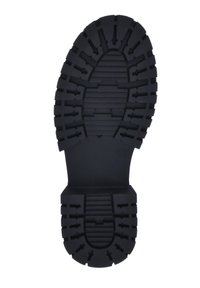 Suela de bota de goma negra con un patrón de relieve profundo, superficie texturizada y múltiples salientes de tracción para una mejor adherencia y durabilidad.