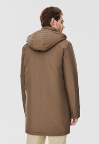 Brązowy wodoodporny parka z kapturem, prostym krojem i gładką fakturą. Posiada boczne kieszenie i średnią długość.