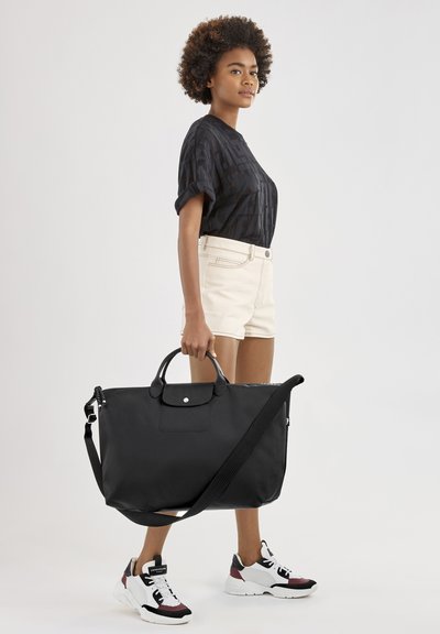 Schwarze Nylon-Tote-Tasche mit doppelten Griffen und verstellbarem Schultergurt. Glatte Textur, minimalistisches Design mit einem Frontknopfschluss.