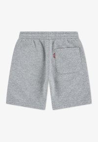 Shorts en coton gris avec une taille élastique, comprenant une poche arrière unique et une petite étiquette logo sur la poche.