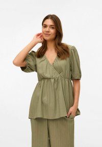 Blusa verde a trama con scollo a V, maniche corte a palloncino e vita arricciata. Presenta un design fluido e una vestibilità rilassata.