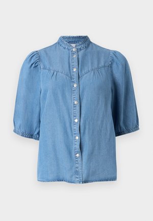 Blouse en denim bleu clair avec manches courtes bouffantes, col montant à volants et fermeture à pression sur le devant.