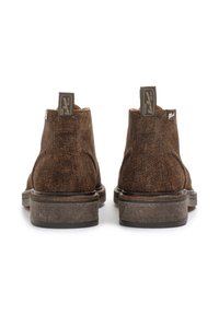 Braune Wildleder-Ankle Boots mit strukturierter Oberfläche, abgerundeten Zehen und gestapelten Absätzen. Verfügt über Markentags auf der Rückseite zur Identifikation.