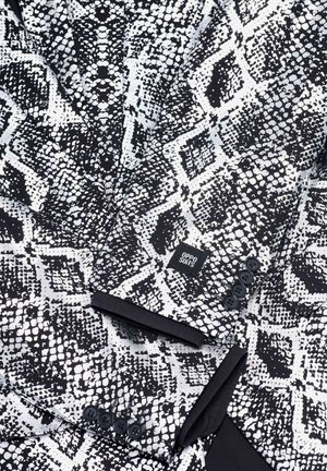 Schwarz-weiß gemusterte Anzugjacke mit strukturiertem Reptildesign, vierknöpfigem Verschluss und einem Etikett von "Oppo Suits".