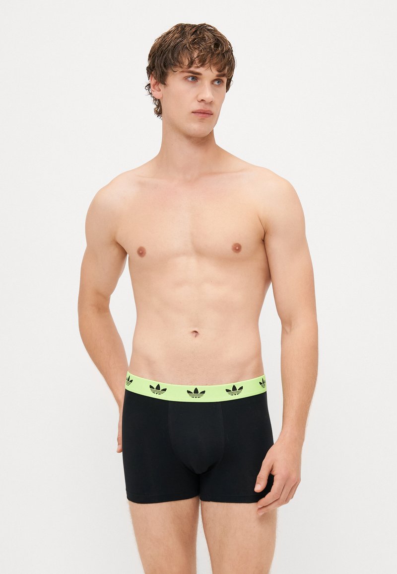 Mustat puuvillabokserit, joissa on leveä neonvihreä vyötärönauha, jossa on lehtilogot. Muotoilu on istuva ja siinä on sileä pinta.