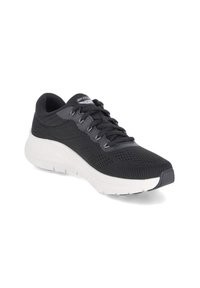 Czarny sportowy but z siateczkową cholewką, miękką białą podeszwą i sześcioma sznurówkami. Na języku znajduje się logo Skechers oraz teksturowane detale.