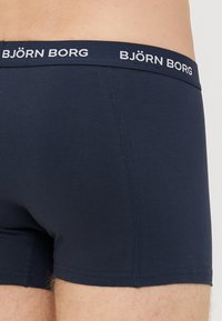 Temno modri moški bokserji so izdelani iz mehke tkanine, z elastiko za pasom in logotipom "BJÖRN BORG" v belem pisanju.
